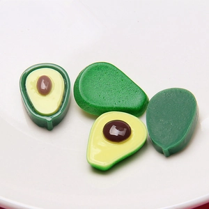 Makroaufnahme von 3D-Avocado-Charms aus Harz mit Textur auf einem weißen Teller