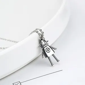 Macro shot of silver robot pendant with G letter detail on a white porcelain edge