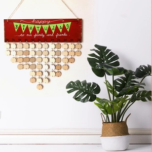 Detail of wooden birthday calendar plaque hanging by a green monstera plant