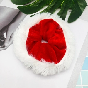 Christmas red velvet scrunchie with white faux fur trim shown on a decorative background
