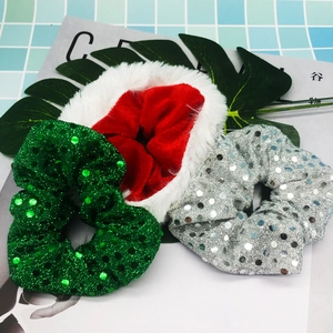 Close-up of three festive scrunchies with green sequins, silver sequins, and red plush trim