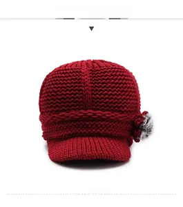 Detail of dark red knit visor hat with thick yarn texture and mixed color faux fur pompom