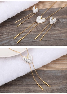 Detail of gold heart pendant necklace with shimmering rhinestones and long tassels