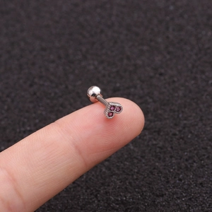 Mini silver heart stud earring with purple zircon stones on a fingertip for size reference