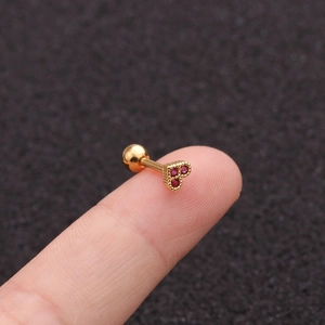Mini gold heart earring with red zircon stone and screw back shown on ear lobe close-up