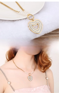 Detail of heart pendant necklace with gold plating, rhinestones and pearl chain