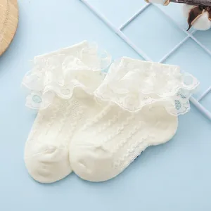 Close-up of baby lace socks in cream white with double-layered ruffles and hollow textures