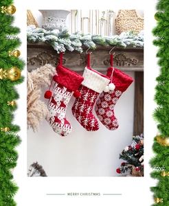 Detail of knitted Christmas stockings with reindeer and tree patterns on a fireplace