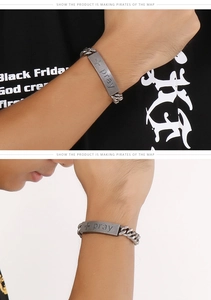 Macro detail of vintage stainless steel prayer bracelet with engraved cross and pray text