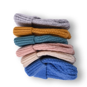 Chunky cable knit beanies in multiple colors stacked vertically on white background