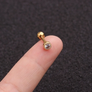 Gold round zircon stud earring with screw back on fingertip for size scale