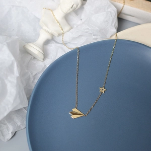 Detail of 14K gold plated paper plane and hollow star pendants on a delicate necklace