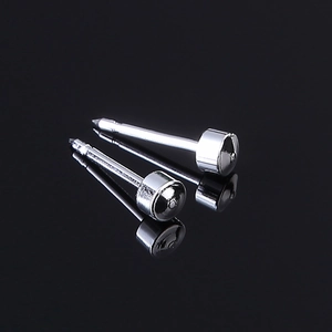 Close-up of two polished silver stainless steel piercing studs with grooved heads