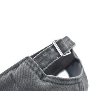 Detail of adjustable metal buckle and stitching on a grey washed cotton baseball cap