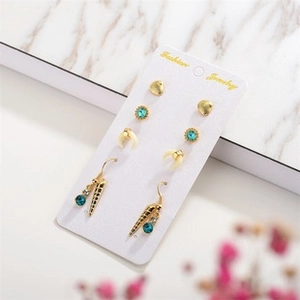 Detailed view of bohemian earring set with turquoise stones and gold charms on white card