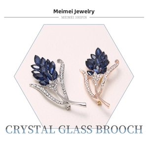 Close-up of leaf-shaped crystal glass brooches in silver and rose gold metal alloy