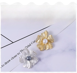 Detailed view of matte flower brooches with pearls and rhinestones in gold and silver