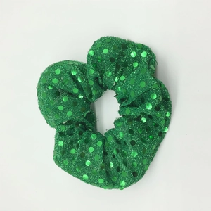 Detail of green sequin scrunchie showing glossy metallic texture and elastic fabric
