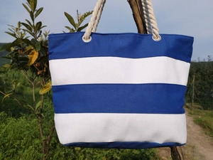 Detail of blue and white striped canvas tote bag with thick rope handles and metal eyelets