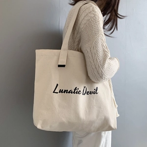 Canvas tote bag with black typography print worn by model showing large capacity