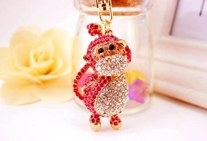 Macro shot of monkey keychain pendant with red and white crystals on golden chain