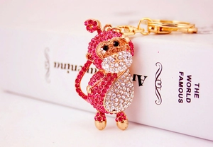 Close-up of pink and white crystal monkey keychain with polished gold metal details
