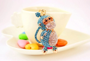 Detailed close-up of a golden monkey keychain featuring blue and clear crystal rhinestones
