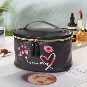 Close-up of black PU leather cylinder makeup bag with pink hearts and red lips pattern