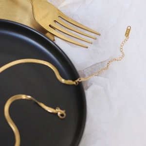 Detail of gold flat snake chain necklace with K14 tag and adjustable extension link