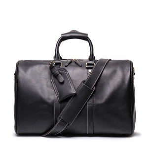 Front view of black leather travel bag with adjustable shoulder strap and gold hardware