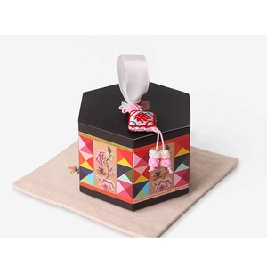 Vue détaillée d'une boîte cadeau hexagonale noire avec motifs floraux et breloque Fu