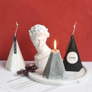 Modern pyramid scented candles in white, grey and black on a white marble tray