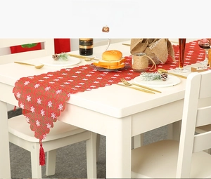 Detail eines roten Weihnachts-Tischläufers mit weißen Sternen und festlichen Quasten
