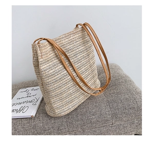 Dettaglio ravvicinato della texture della borsa in paglia con sottili manici in pelle