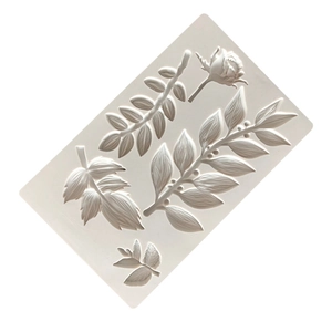 Detail of white silicone mold featuring intricate leaf, branch and rosebud patterns for baking
