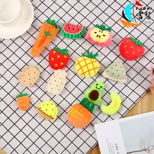 Flat lay of colorful plush fruit and vegetable brooches on a checkered tablecloth