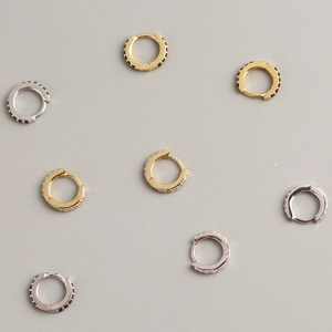 Close-up of gold and silver 925 sterling silver hoop earrings with black and white stones