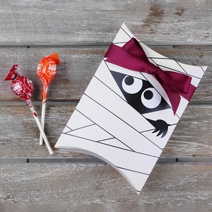 Halloween mummy pattern pillow gift box with burgundy ribbon on vintage wood background