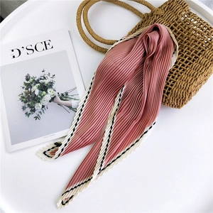 Dusty pink pleated silk scarf with black and white geometric border on straw bag
