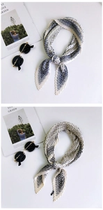 Detailed view of pleated silk scarves with blue and black geometric wave patterns