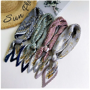 Close-up of pleated silk scarves in four colors featuring classic equestrian chain patterns