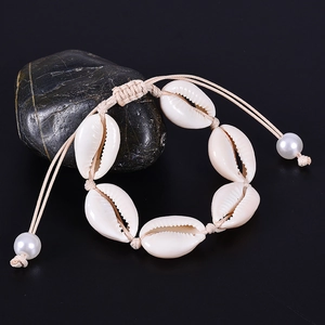 Handmade shell bracelet with natural white sea shells and pearls on dark stone