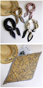 Detail of pleated silk scarf featuring vintage gold chain print and contrast hem