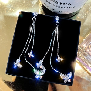 Detailed view of silver butterfly tassel earrings with sparkling crystals in a jewelry box