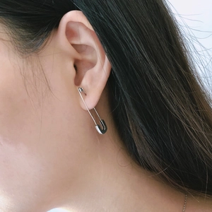 Silver safety pin earrings on ear model showing scale and elegant hanging style