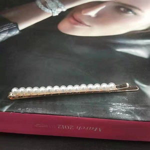 Barrette dorée élégante avec rangée de perles blanches sur base métallique minimaliste
