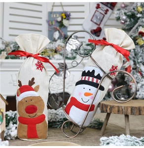 Detailed view of linen Christmas wine bottle bags with reindeer and snowman designs