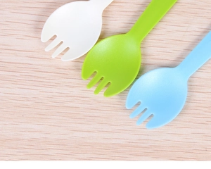Detailed view of colorful disposable plastic dessert sporks on a light wood background
