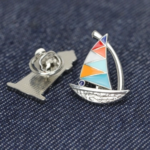 Elegant vintage sailboat enamel brooch pin with colorful sails on denim background
