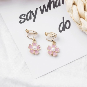 Pink floral clip-on earrings with gold trim and central pearl on a white background
